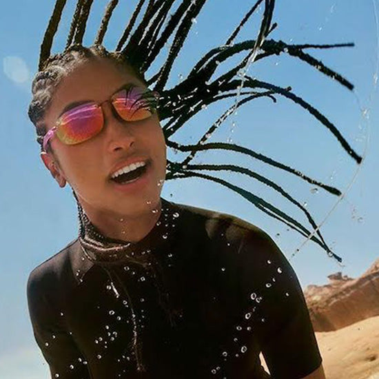 Frau am Strand nach dem Surfen trägt Maui Jim Sonnenbrille mit stilvoller Fassung und polarisierten Gläsern.